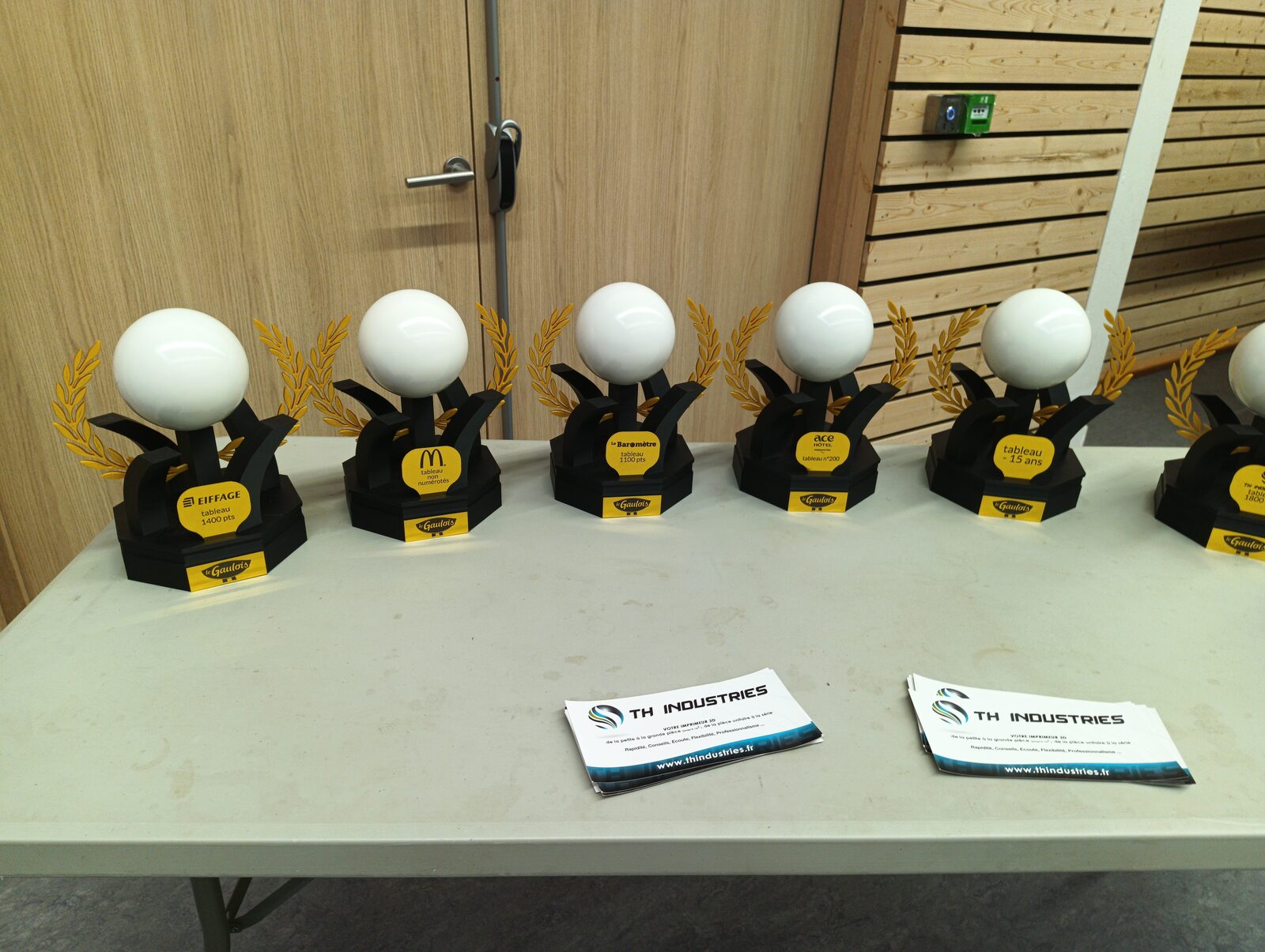 Trophées personnalisés imprimés en 3D avec lauriers dorés et logos d'entreprises, réalisation TH Industries
